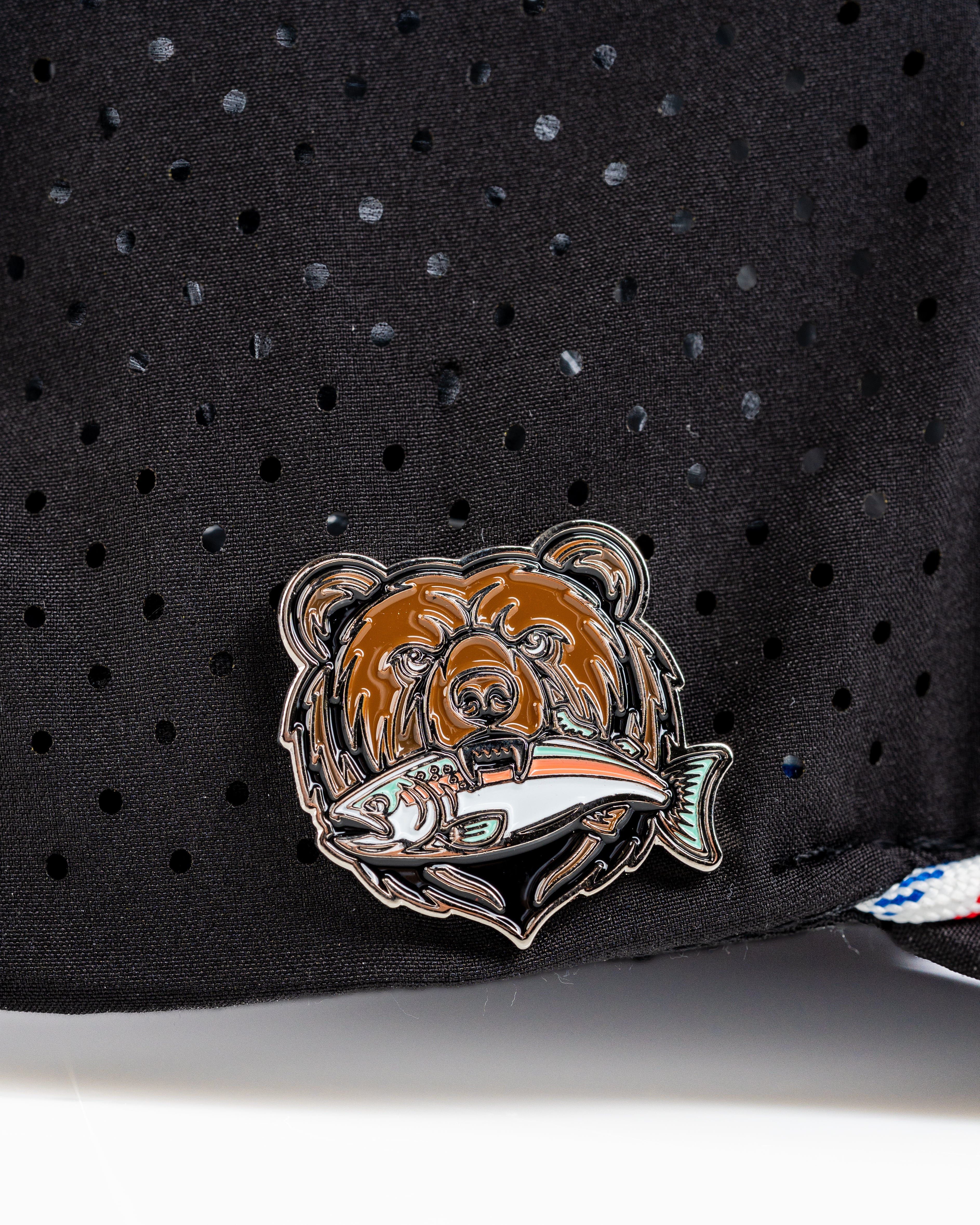 Perforated black rope hat featuring a Grizzly bear emblem holding a fish, perfect for stylish golfers.