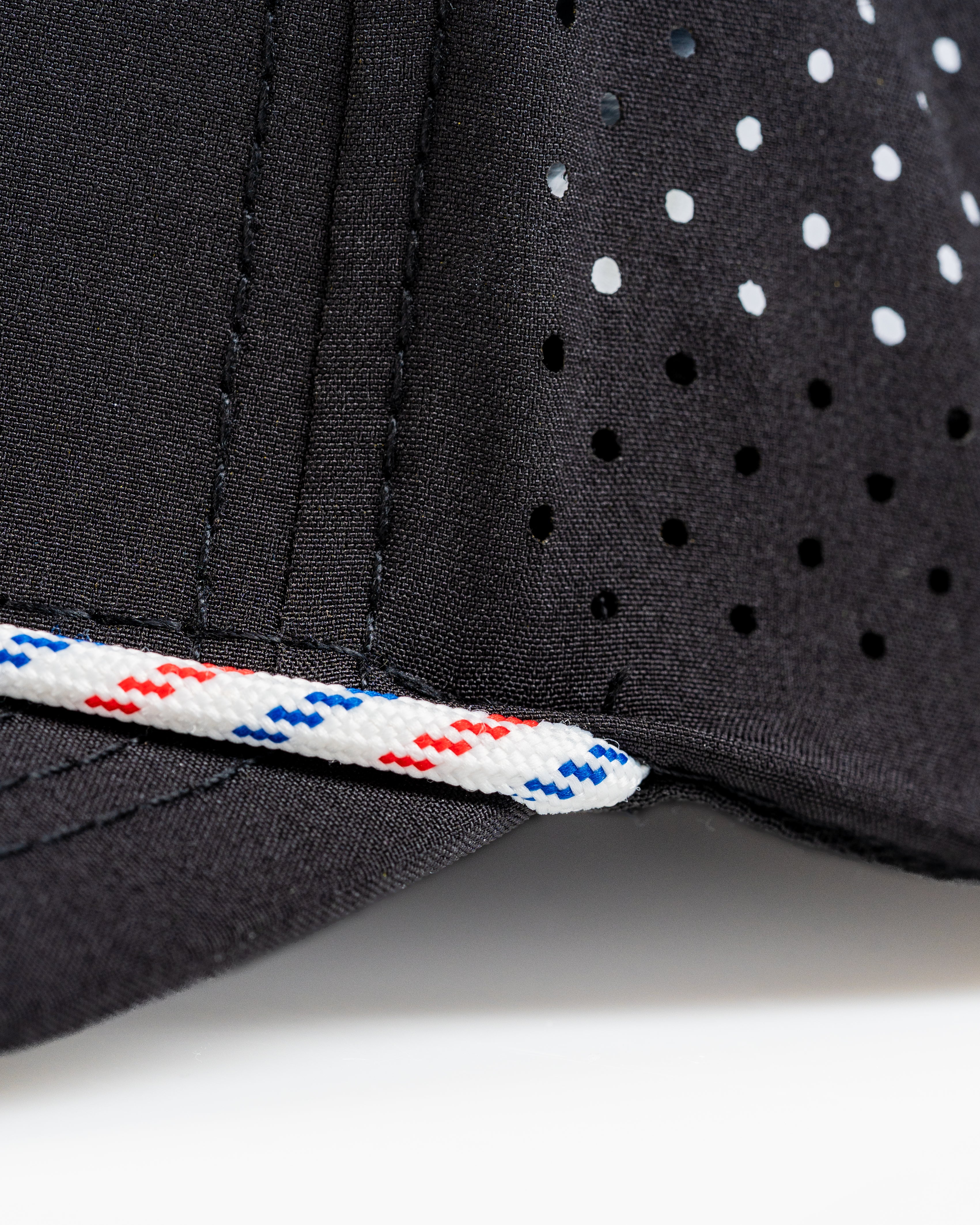 Perforated black rope hat featuring a stylish red and blue accent, designed for bold golfers seeking unique accessories.