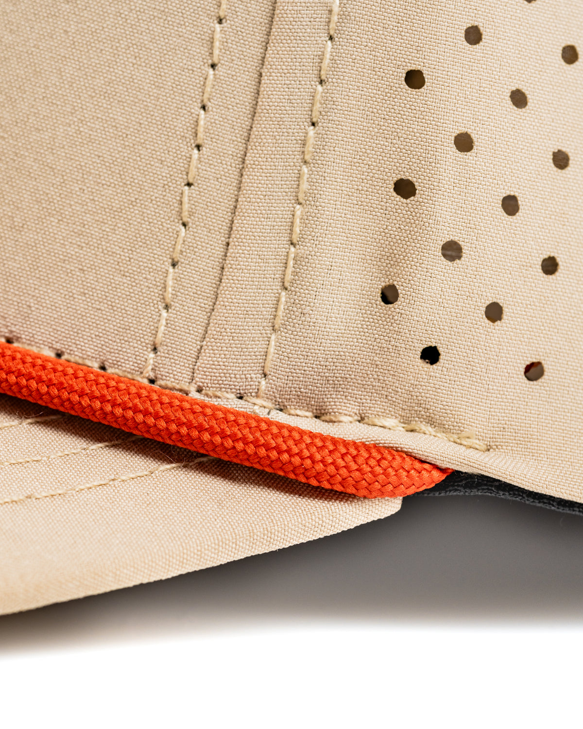 Perforated rope hat in beige with orange detailing, designed for golfers seeking style and breathability on the course.
