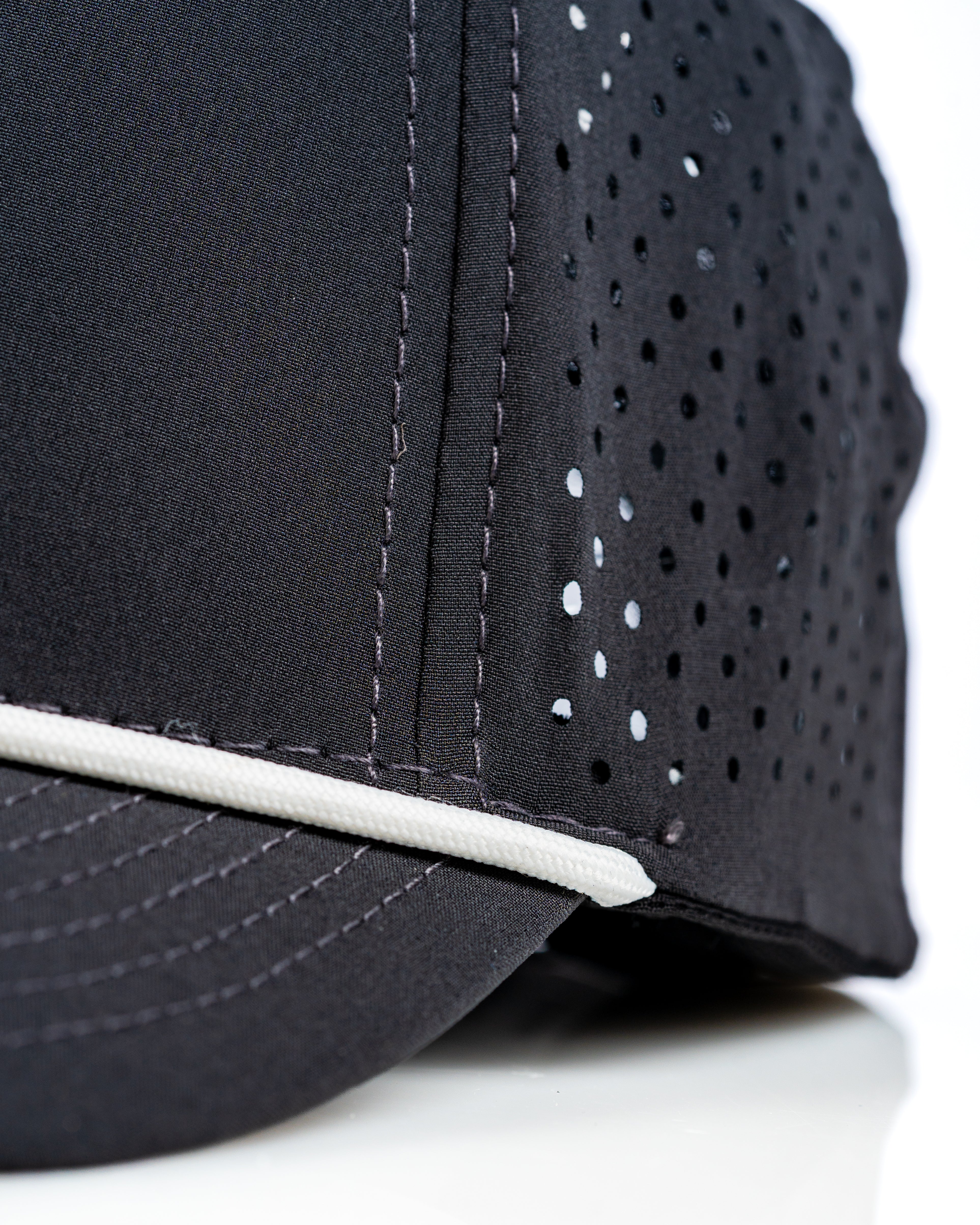 Perforated rope hat in black with white accents, featuring ventilation holes for breathability and style.