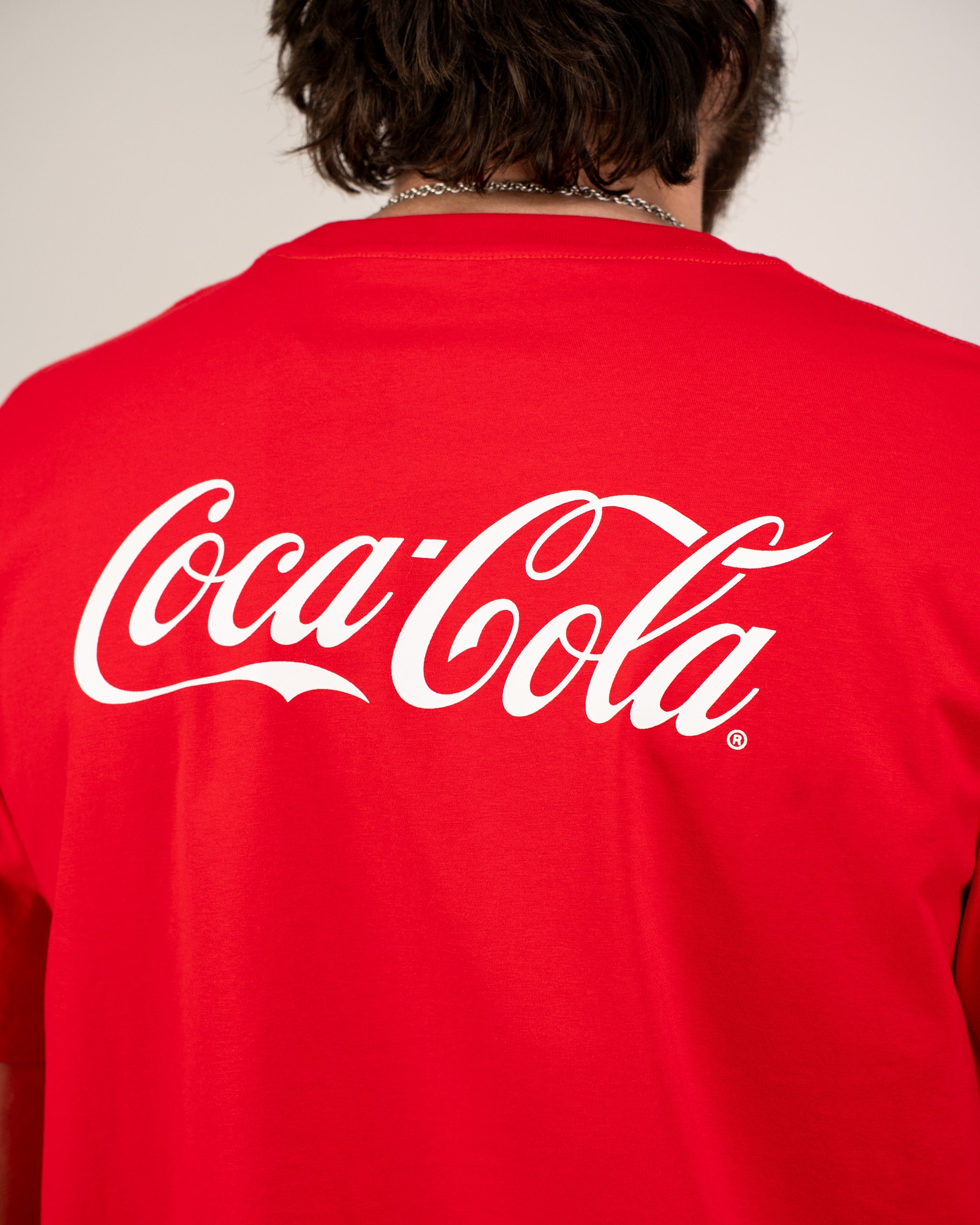 Red Coca-Cola tee shirt featuring the iconic logo prominently displayed on the back. Ideal for casual wear.