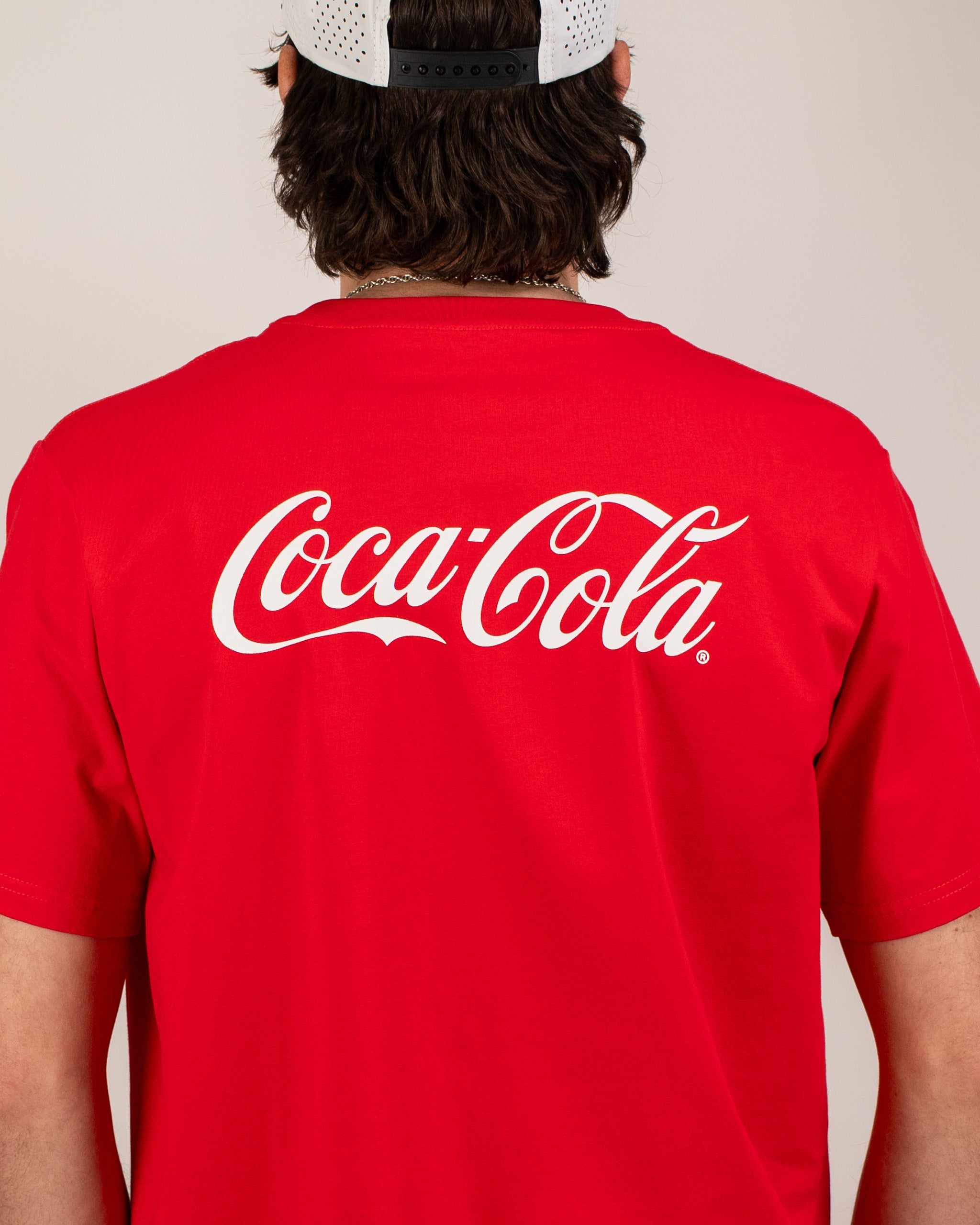 Red Coca-Cola tee shirt featuring the iconic logo prominently displayed on the back, perfect for casual wear.
