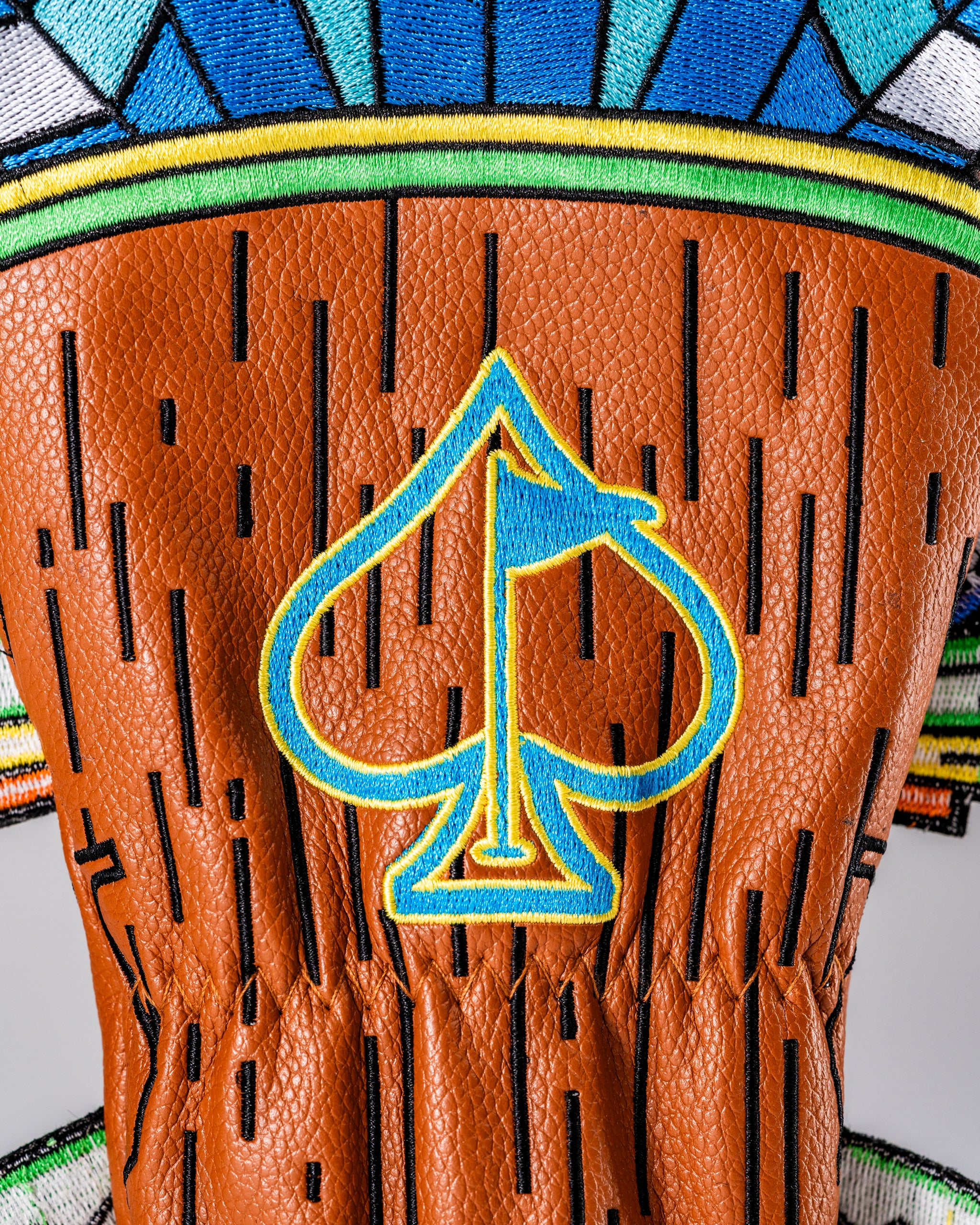 Colorful Tiki hybrid golf cover featuring a vibrant design with a spade logo and textured leather finish.