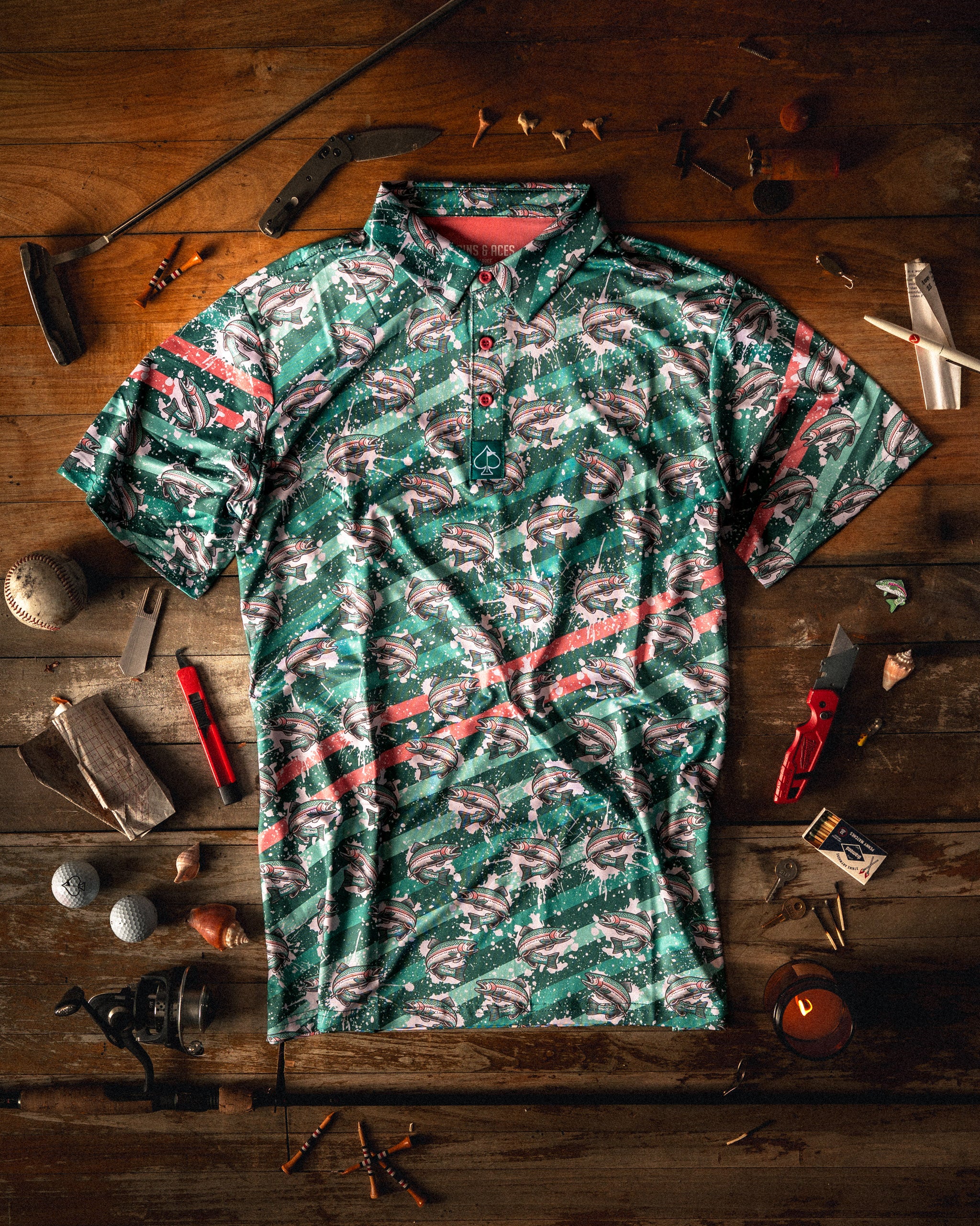 Bold golf shirt featuring a trout splatter design in vibrant colors, surrounded by golf accessories and tools.