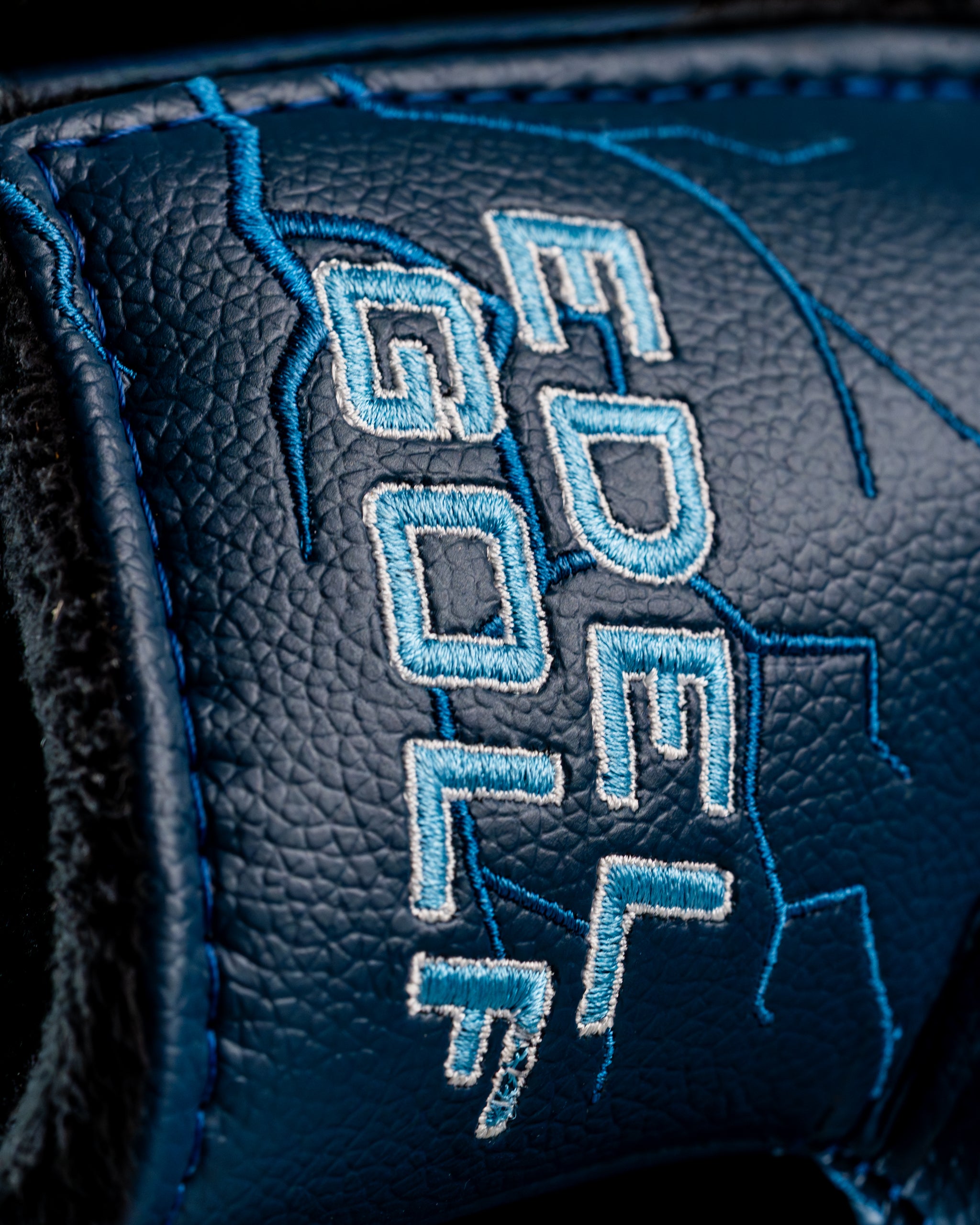 Close-up of the Edel Twister Putter headcover featuring blue leather with detailed embroidery of the brand name.