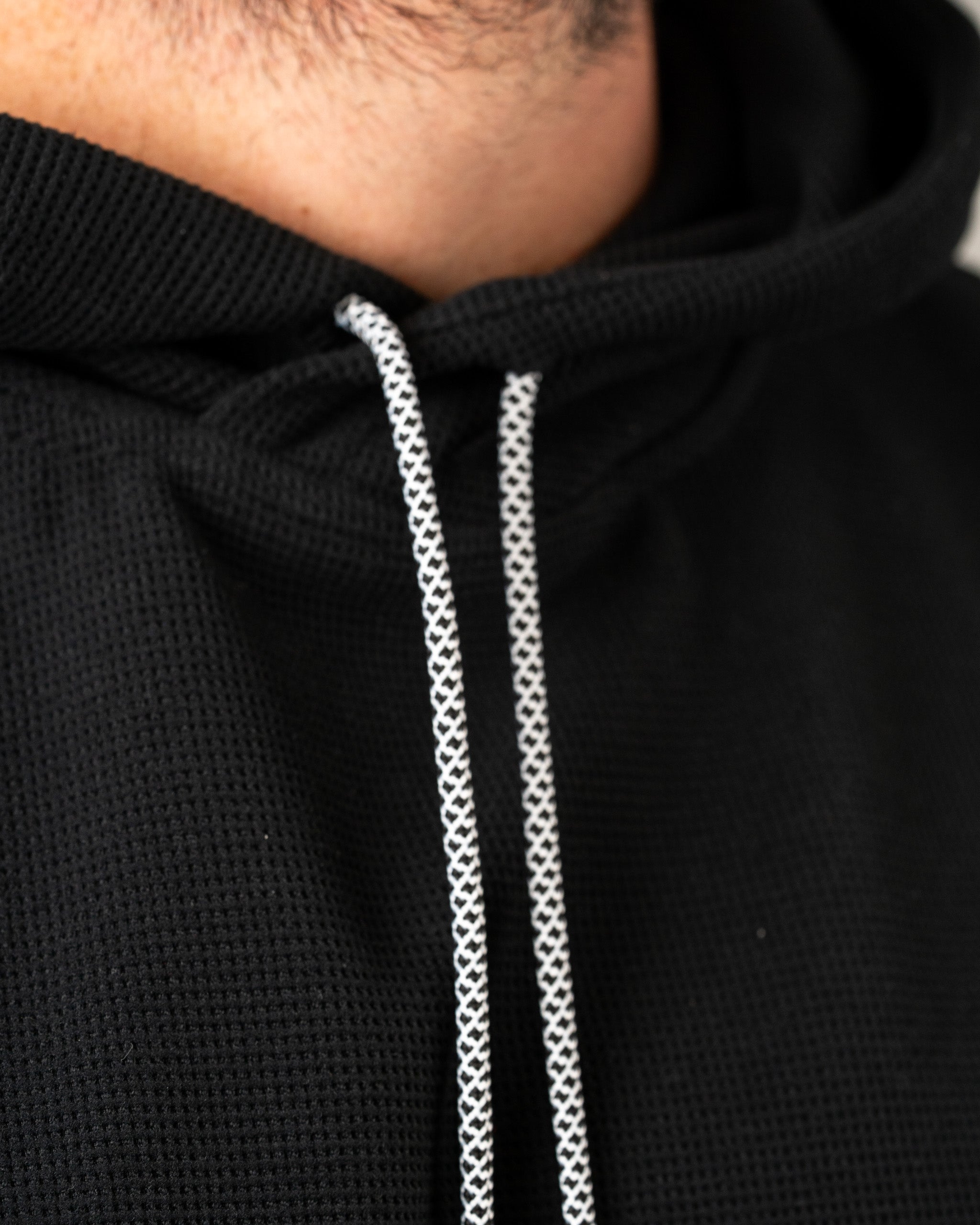 Close-up of the Player Preferred Waffle Grid Hoodie in Obsidian, showcasing the textured fabric and contrasting drawstrings.