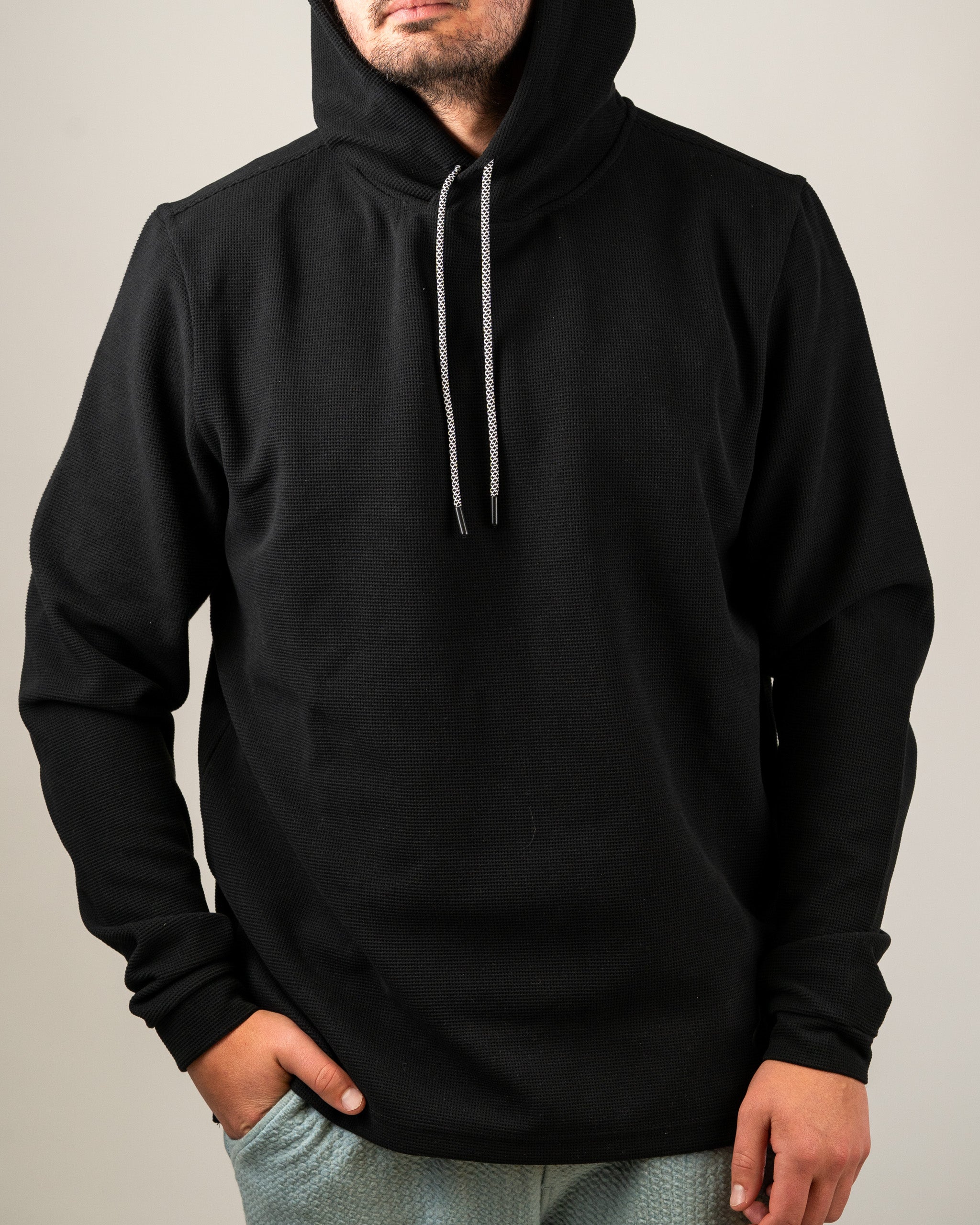 Men's black waffle grid hoodie with a drawstring hood, designed for comfort and style on and off the golf course.