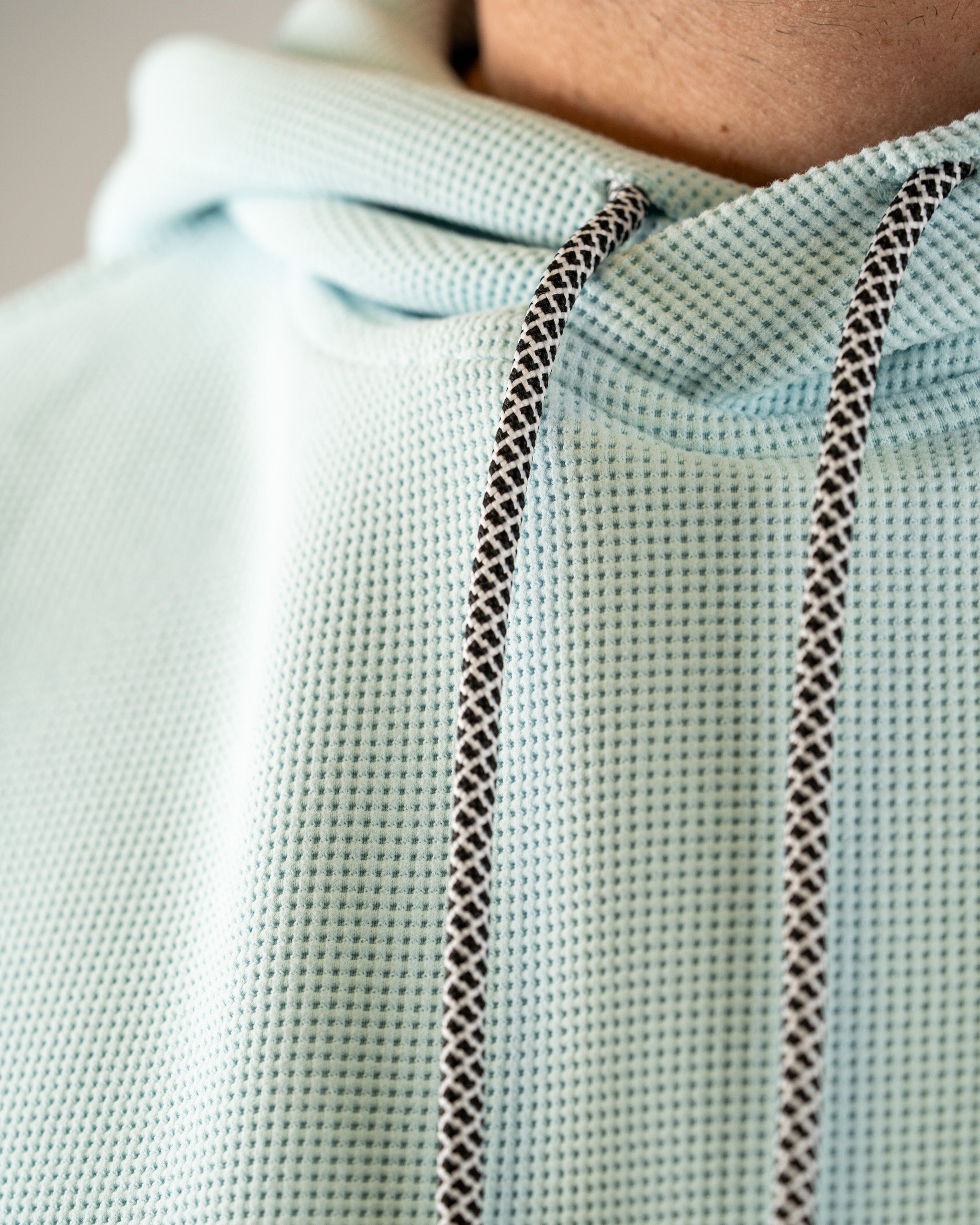 Ice blue waffle grid hoodie featuring a textured fabric and contrasting drawstrings, perfect for stylish comfort on the course.
