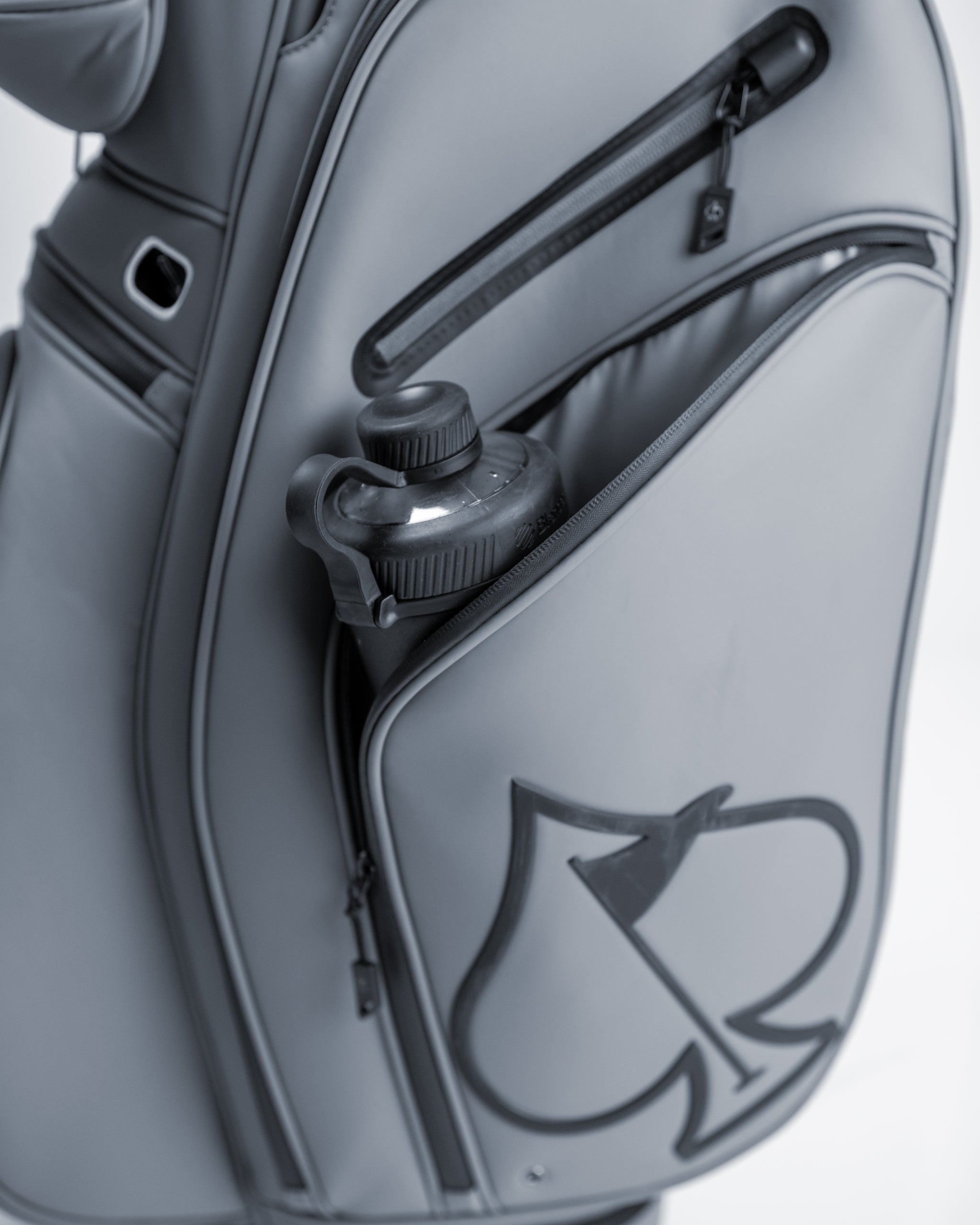 Gray golf bag with black zipper accents and bold logo, featuring a water bottle holder and multiple compartments for acces...