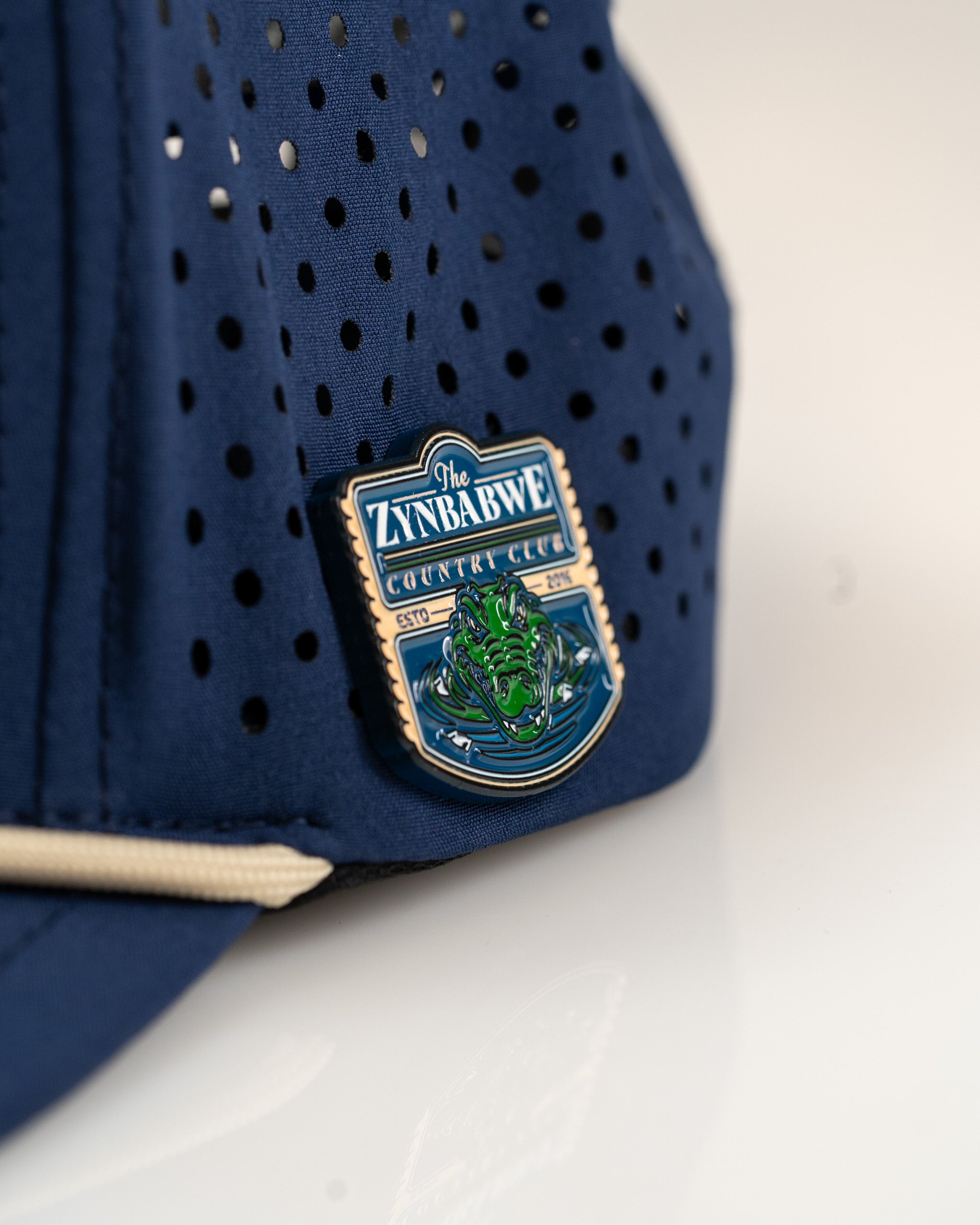 Navy perforated rope hat featuring a Zynbabwe Country Club emblem, designed for stylish golfers.